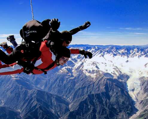 Tandem skydive midair overlooking frosty mountains.