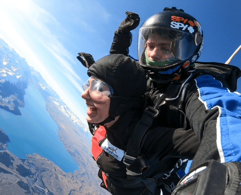 Two people skydiving overlooking the lake.